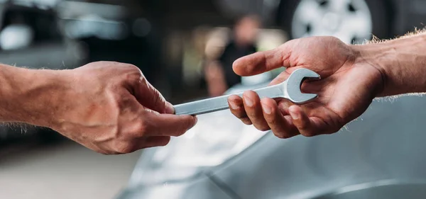 Vue recadrée des mécaniciens tenant clé dans l'atelier de réparation automobile — Photo de stock