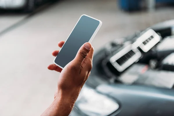 Vue partielle du travailleur à l'aide d'un smartphone avec écran vierge dans un atelier de mécanique — Photo de stock