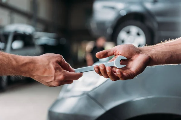 Vista parcial de la mecánica de automóviles con llave en el taller de reparación — Stock Photo