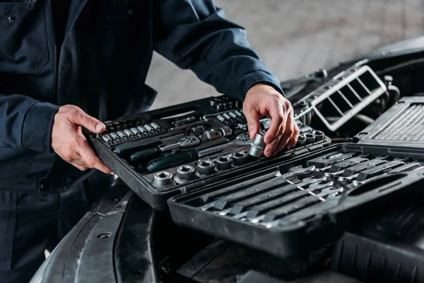 Vista parcial de mecánico con caja de herramientas en taller de reparación de automóviles - foto de stock