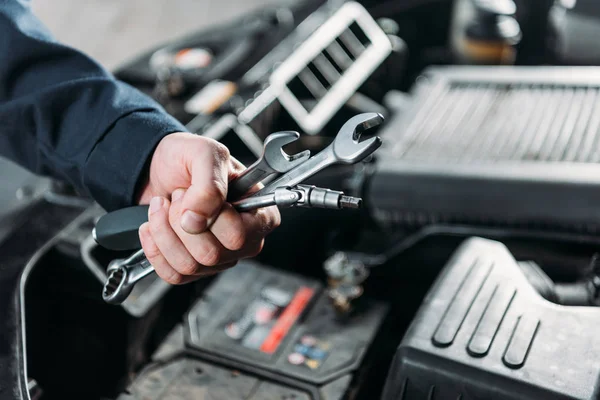 Cropped view of mechanic holding wrenches in hand — Stock Photo