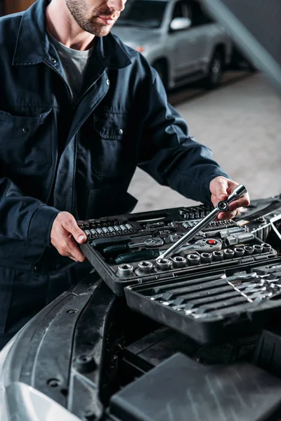 Vista recortada de mecánico con caja de herramientas en taller de reparación de automóviles - foto de stock