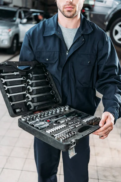 Cropped view of workman in uniform holding tool case — Stock Photo