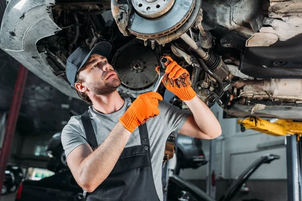 Mechanic repairing car without wheel in workshop — Stock Photo