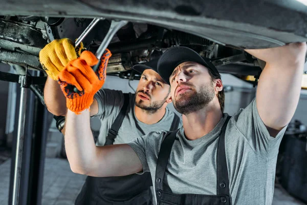 Professional auto mechanics working with car and tools in workshop — Stock Photo