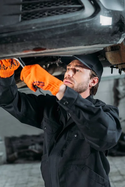 Male mechanic repairing a car in auto repair shop — Stock Photo