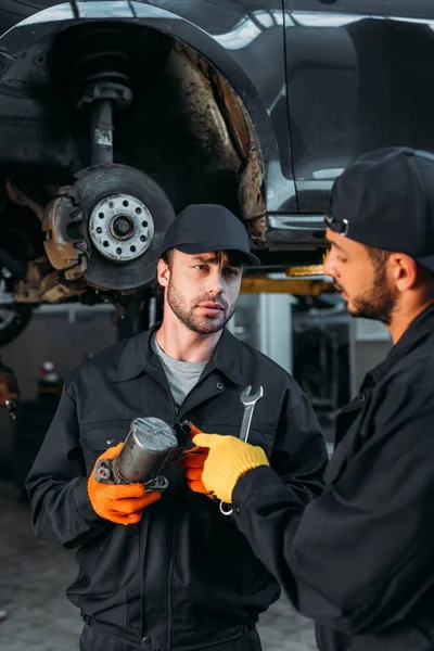 Trabajadores manuales de reparación de automóviles con herramientas en taller mecánico - foto de stock