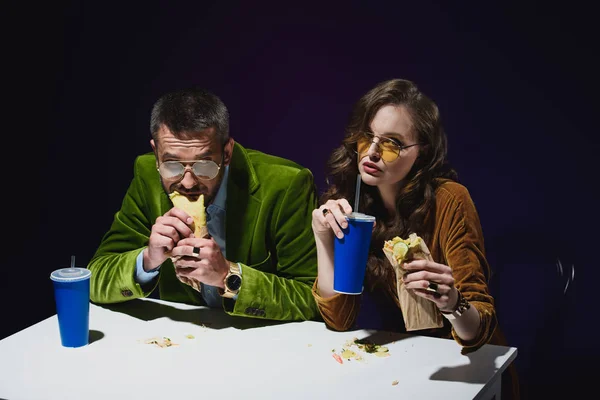 Portrait of couple in luxury velvet clothing with shawarma and soda drinks sitting at table with dark background behind — Stock Photo