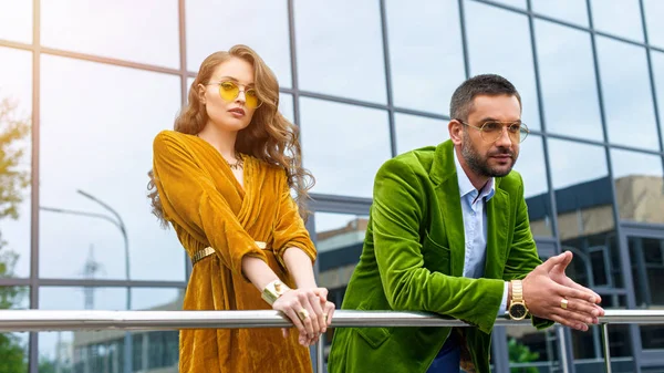 Retrato de pareja atractiva en ropa de moda de pie en la calle y mirando a la cámara - foto de stock