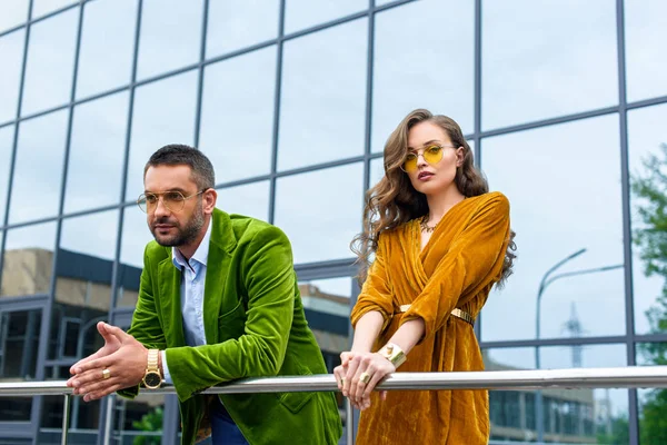 Portrait de couple attrayant dans des vêtements à la mode debout sur la rue et regardant la caméra — Photo de stock