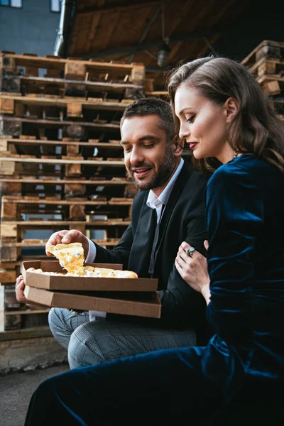 Vista lateral do casal elegante com pizza de queijo italiano descansando na rua — Fotografia de Stock