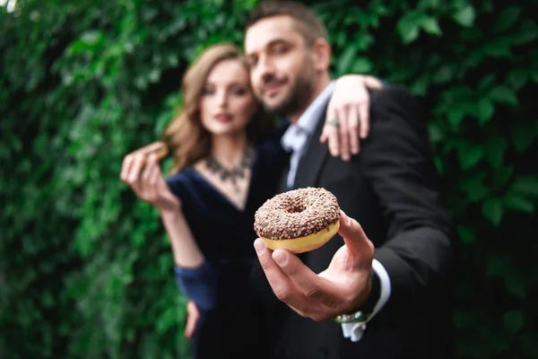 Foyer sélectif de couple à la mode avec beignets au chocolat avec feuillage vert derrière — Photo de stock