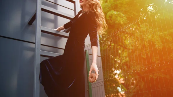 Tiro recortado de mujer en vestido de lujo con rosquilla de chocolate en la mano colgando en la escalera en la calle - foto de stock