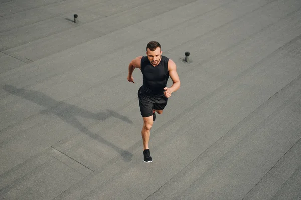 Высокий угол обзора красивого спортсмена, бегущего по крыше — стоковое фото
