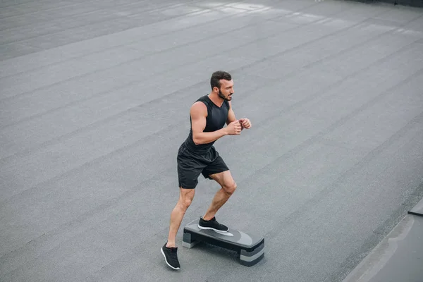 High angle view of handsome sportsman training with step platform on roof — Stock Photo