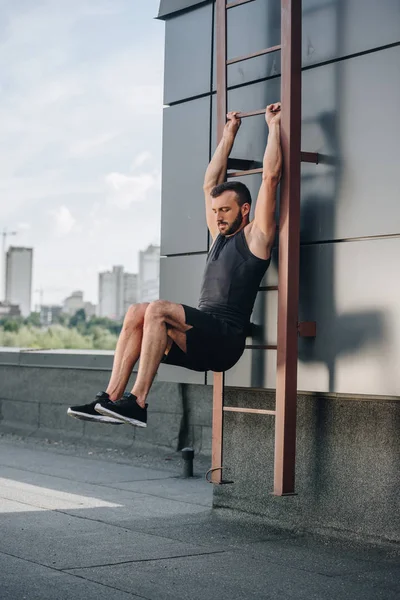 Handsome sportsman training on ladder on roof — Stock Photo