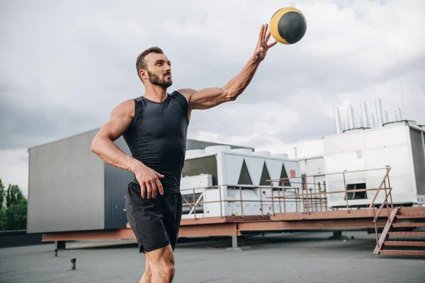 Bonito desportista formação com medicina bola no telhado — Fotografia de Stock