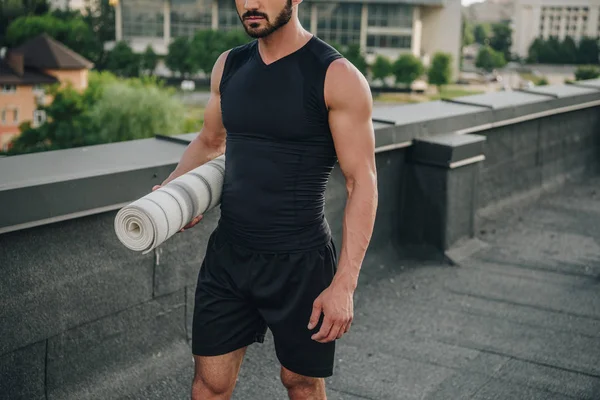 Cropped image of man walking with yoga mat on roof — Stock Photo