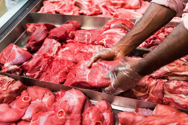 Abgeschnittenes Bild einer männlichen Verkäuferin, die rohes Fleisch im Supermarkt einnimmt — Stockfoto