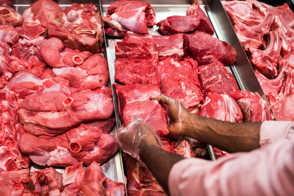 Männlicher Metzger nimmt rohes Fleisch im Supermarkt — Stockfoto