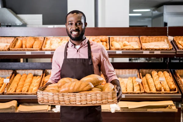 Foyer sélectif de l'assistant de magasin homme afro-américain dans le tablier avec des pains au supermarché — Photo de stock