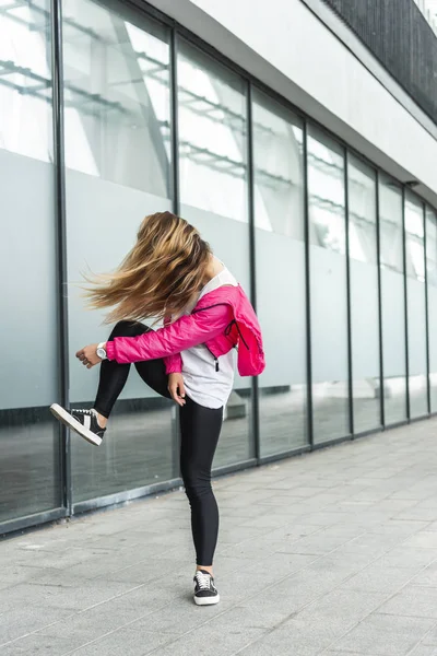 Молодая стильная женщина с затемненным лицом, танцующая волосами на городской улице — стоковое фото