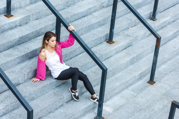 Hochwinkelaufnahme einer stilvollen asiatischen Frau, die auf einer Treppe in einer städtischen Straße sitzt — Stockfoto