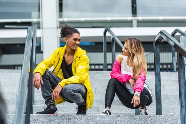 Sonriente joven pareja multiétnica bailando en las escaleras en la calle urbana - foto de stock