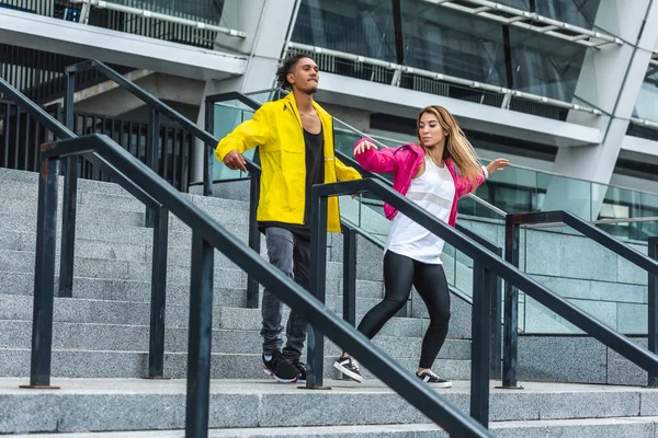 Junges multiethnisches Paar tanzt auf der Treppe einer städtischen Straße — Stockfoto