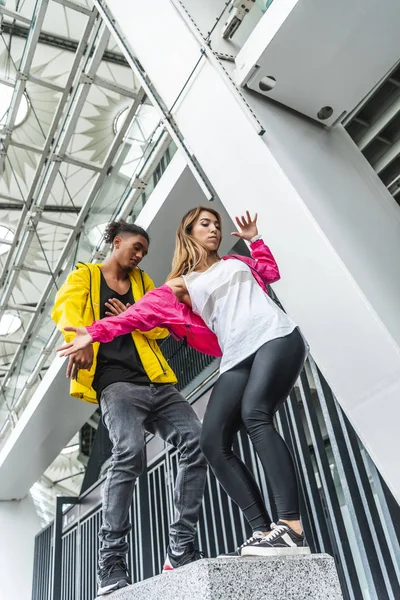 Low angle view of multiethnic couple of urban dancers dancing at street — Stock Photo