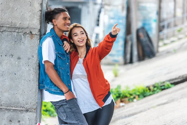 Feliz asiático mulher apontando por dedo para misto raça namorado no cidade rua — Fotografia de Stock