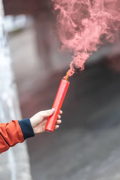 Cropped image of young woman holding red smoke bomb at city street — Stock Photo