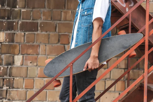 Cropped image of stylish man holding skateboard at urban street — Stock Photo