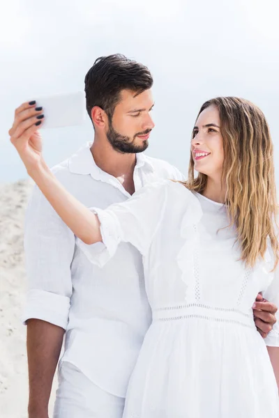 Loving young couple in white clothes taking selfie in desert — Stock Photo