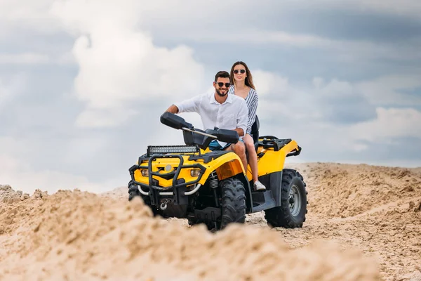 Activa pareja joven montando vehículo todo terreno en el desierto en el día nublado - foto de stock
