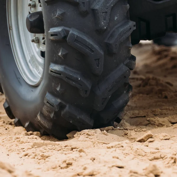 Cropped shot of wheel of all-terrain vehicle on sand — Stock Photo