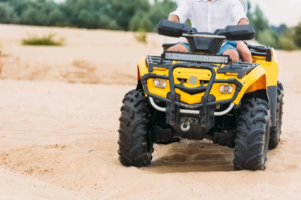 Plan recadré de couple chevauchant véhicule tout-terrain sur le sable — Photo de stock