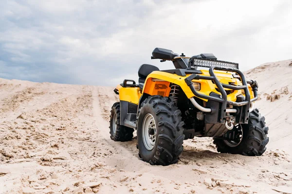 Vista dal basso del moderno veicolo giallo all-terrain in piedi nel deserto nella giornata nuvolosa — Foto stock