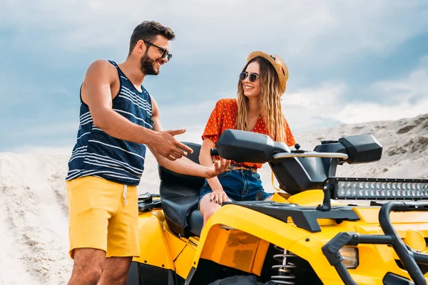 Heureux jeune homme enseignant à sa petite amie comment monter atv dans le désert — Photo de stock