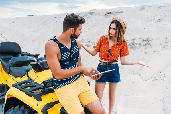Lost young couple with ATV using digital tablet in desert — Stock Photo