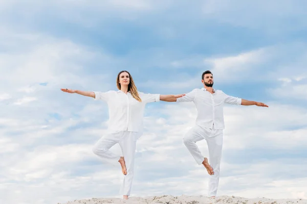 Bottom view of fit young couple practicing yoga in tree pose (Vrksasana) on sandy dune — Stock Photo