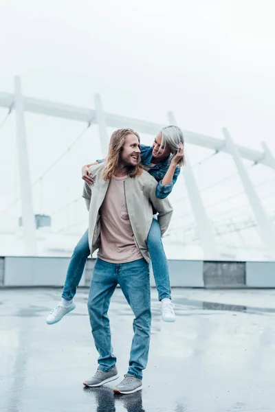 Heureuse femme piggyback sur copains retour sur le parking de stade — Photo de stock