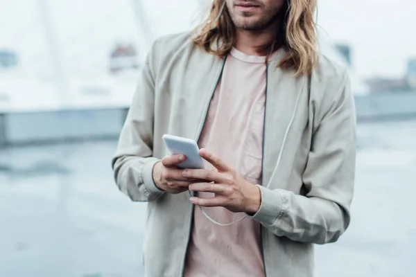 Plan recadré d'un jeune homme utilisant un smartphone dans la rue par temps nuageux — Photo de stock
