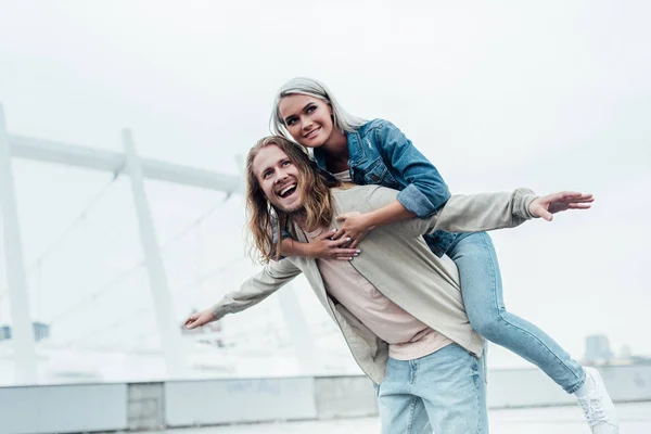 Happy young woman piggybacking on boyfriends back — Stock Photo