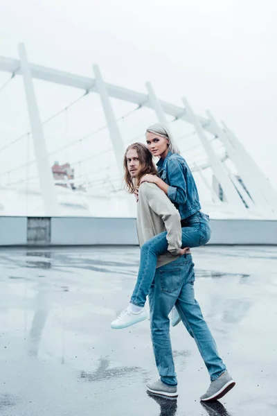 Atractivo joven mujer piggybacking en novios espalda - foto de stock