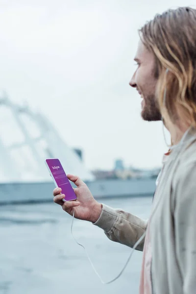 Happy young man using smartphone with instagram app on screen on street — Stock Photo