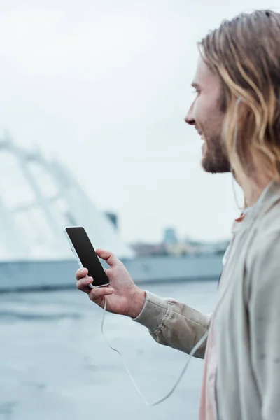 Beau jeune homme utilisant un smartphone avec écran blanc sur la rue — Photo de stock