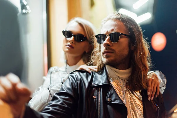 Jovem casal atraente em roupas elegantes olhando para longe na rua à noite — Fotografia de Stock