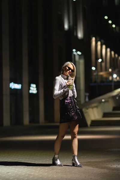 Stylische junge Frau mit Mojito im Plastikbecher auf dunkler Straße — Stockfoto