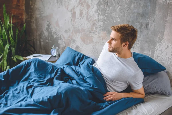 Selbstbewusster junger Mann wacht morgens zu Hause im Bett auf — Stockfoto